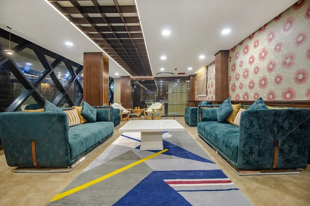 The guest lounge, with teal velvet sofas facing a low marble table